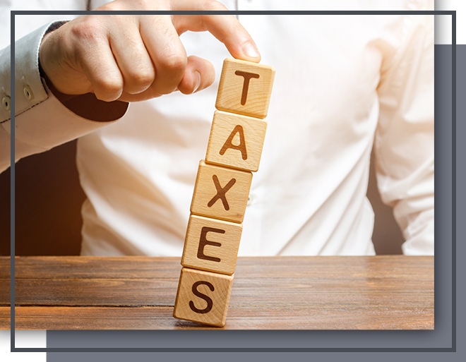 Image of a man pushing over some blocks that spell the word taxes