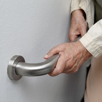 elderly person uses a handrail to assist them on the wall 