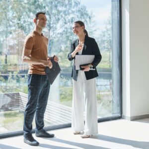 real estate agent stands by large window with man