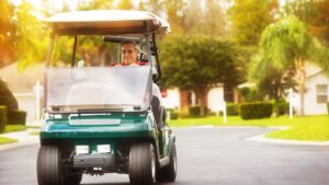 senior man driving a golf cart in sunny landscape