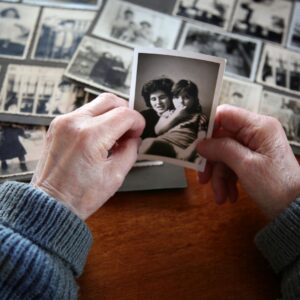 hands hold an old photo over a table