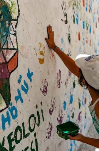 person presses hand against wall with colorful handprints