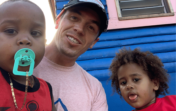 man sits with kids outside a colorful building