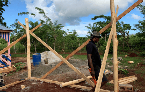 man wearing a shade hat and shorts walks across construction site