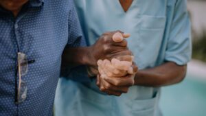 healthcare worker holds patients hand for support