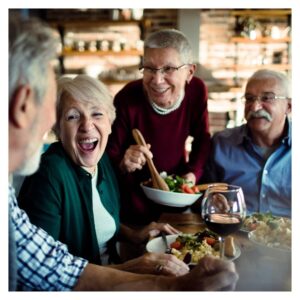 a group of seniors smile and laugh sitting at table