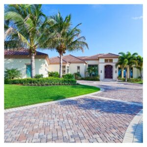 house with pavers in the driveway and palm trees