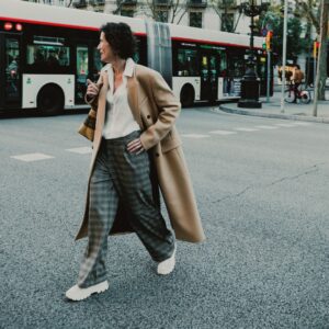 woman crosses street with bus in background