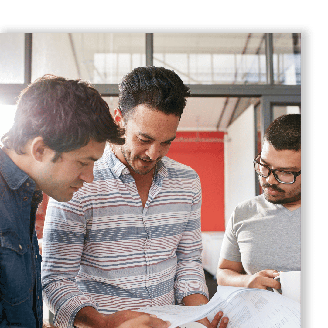 men stand beside each other looking at document in an office