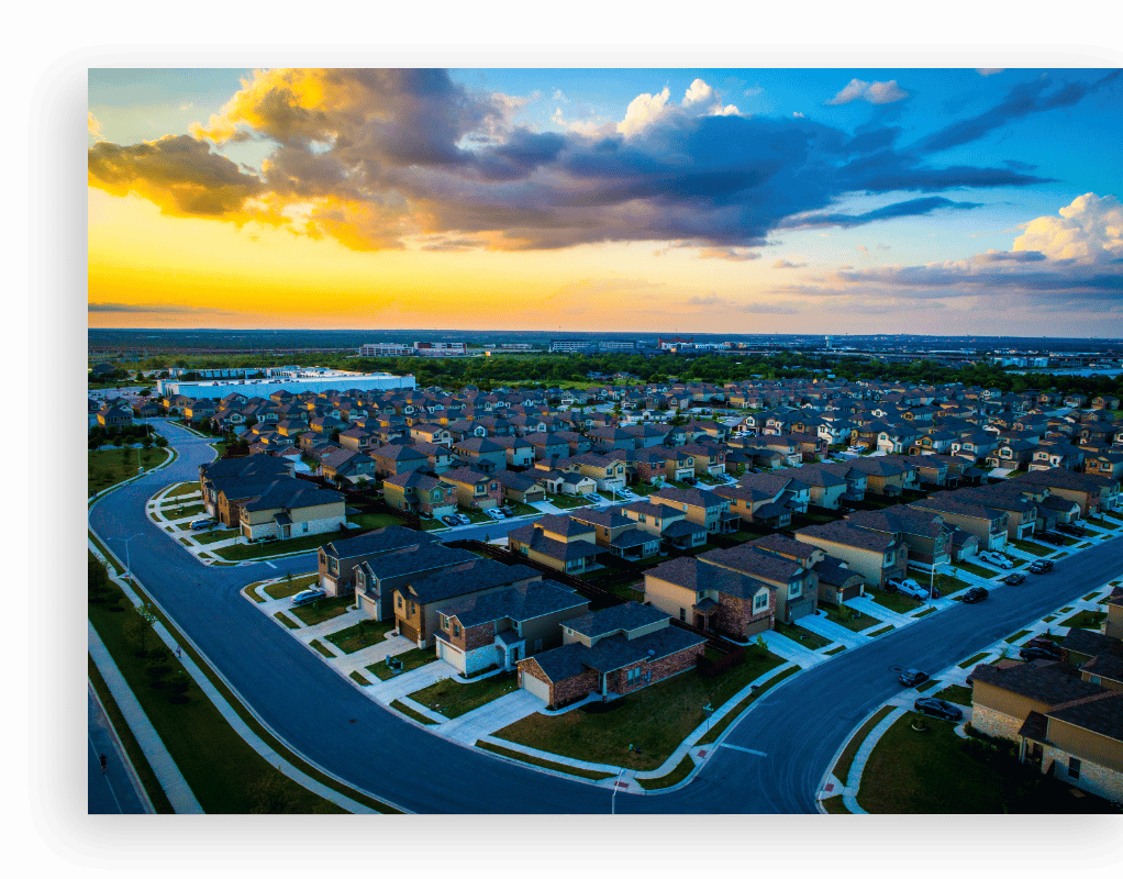areal view of neighborhood with many houses and sunset