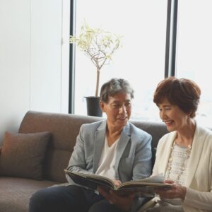 older husband and wife wit on couch looking at photo album together